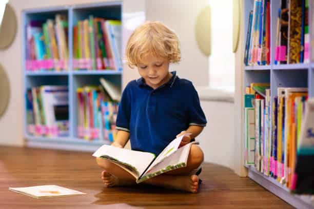 Child in school library. Kids read books. Little boy reading and studying. Children at book store. Smart intelligent preschool kid choosing books to borrow.